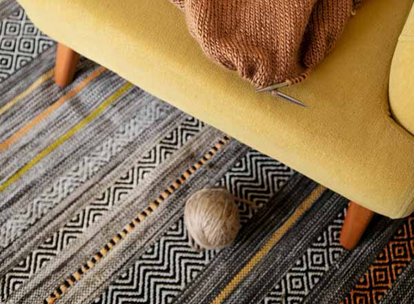 Bord d’un tapis redressé par un meuble