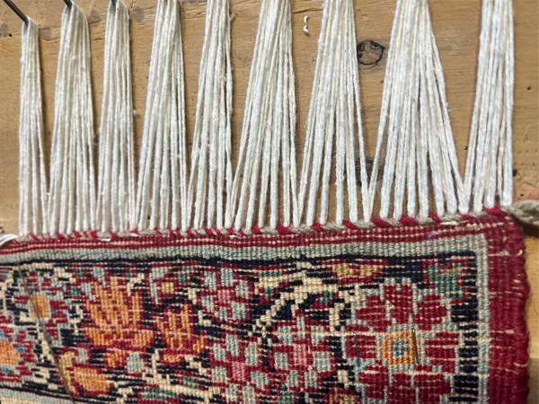 Comment choisir le tapis d’Orient noir parfait pour votre intérieur ? Restauration des franges de tapis sur établi avec clous
